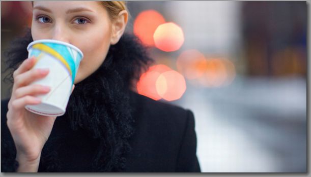 Woman drinking coffee on city sidewalk